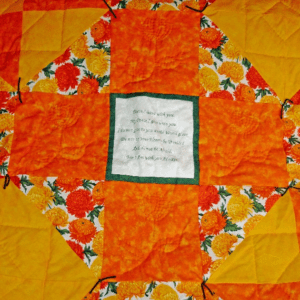 Lap quilt with a cross configuration enclosing a the Bible verse John 14:37 in yellow and orange fabrics