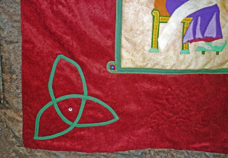 Green Trinity know with a gemstone embedded in the center from a quilt on the Lindisfarne Gospels