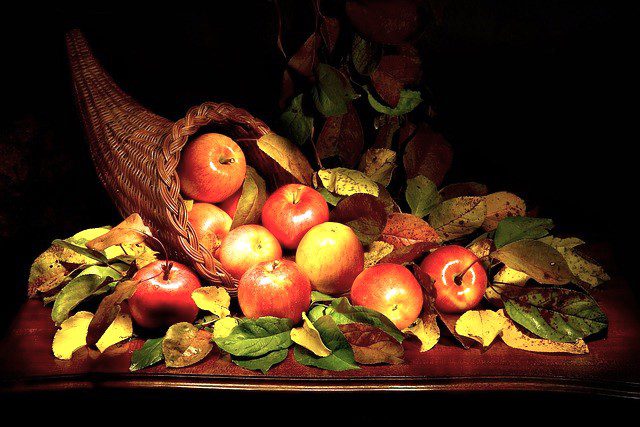 Cornucopia filled with red shiny apples and bright green leaves