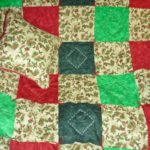 Holiday quilt with matching pillow of winter pine cones and berries set into squares of red, dark and light green fabrics