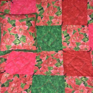 Lap quilt with matching pillow of gold-tinted red poinsettias set with red, pink and dark green fabric squares