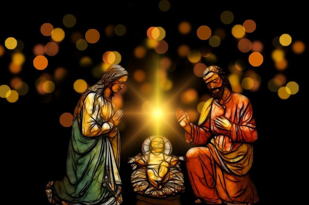 Manger scene lit by the glow of Christ's halo against a dark multi-coloured background