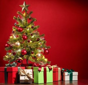 Decorated Christmas tree with gifts underneath against a red-shaded background