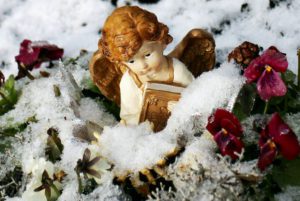 Ceramic angel in a snowbank surrounded by wilted violets