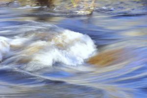 Waves of white water streaming over a rocky river bed