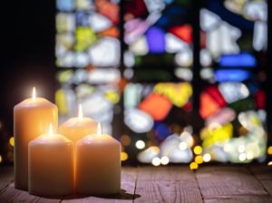 Candle flames flickering against a stained-glass background