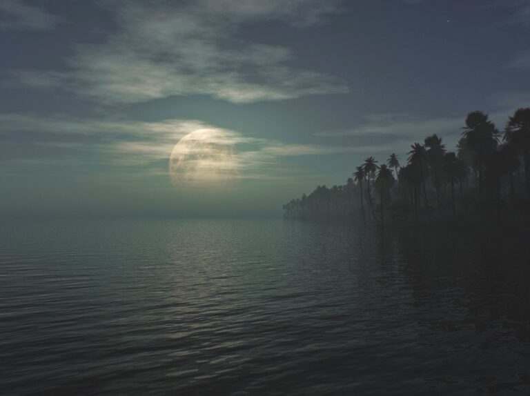 Full moon shining thru the clouds over the still ocean water