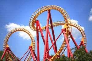 Yellow and red roller-coaster ride against a bright blue sky.