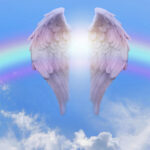 pair of angel wings infront of a rainbow arc against a beautiful blue sky with fluffy clouds ideal for a spiritual or religious blessing theme