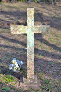 White cross with a withered white rose at its base