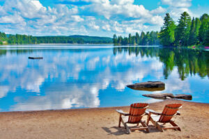 Sunny beach at the lake-side with forest and mountain in the background