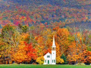 White clapboard church against bright-colored Fall foliage