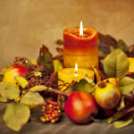 Fall arrangement of fruits and flowers surrounding a lighted candle