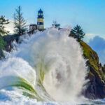 Waves crash against a rocky point showing a lighthouse