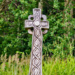 Celtic cross - a wooden cross in a meadow by the forest
