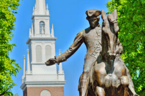 Statue of Paul Revere, with the steeple of the Old North Church in the background.