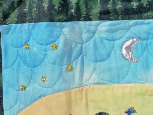 A silver lame fabric crescent moon surrounded by 3 yellow stars