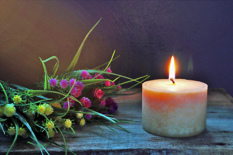 Single lit candle with dried flowers
