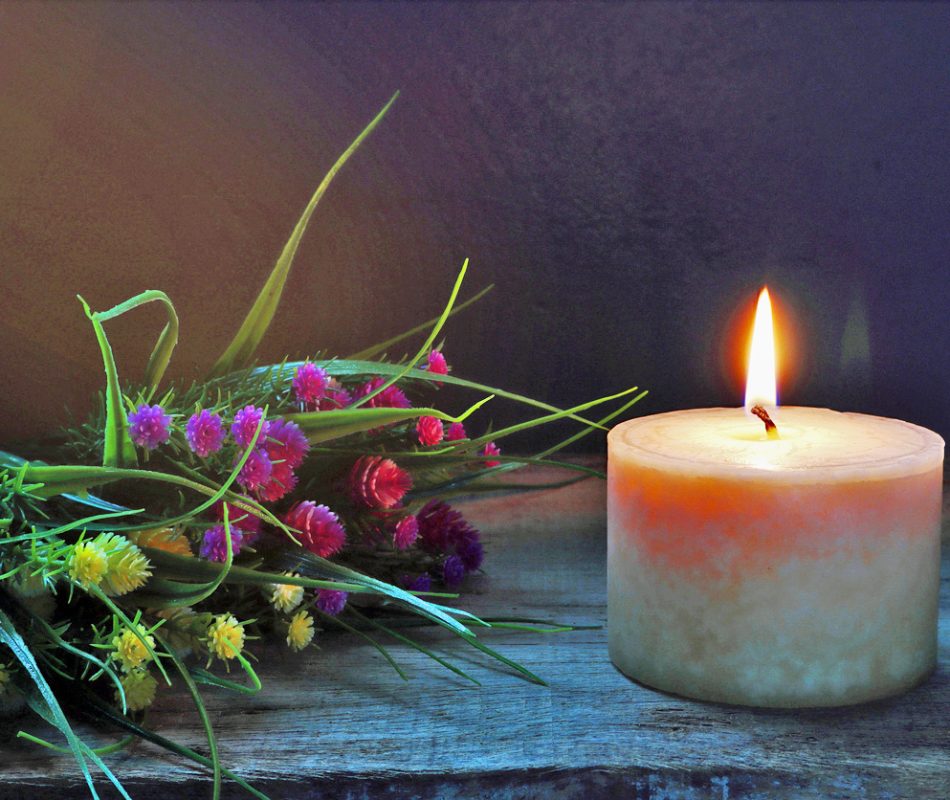 Single lit candle with dried flowers