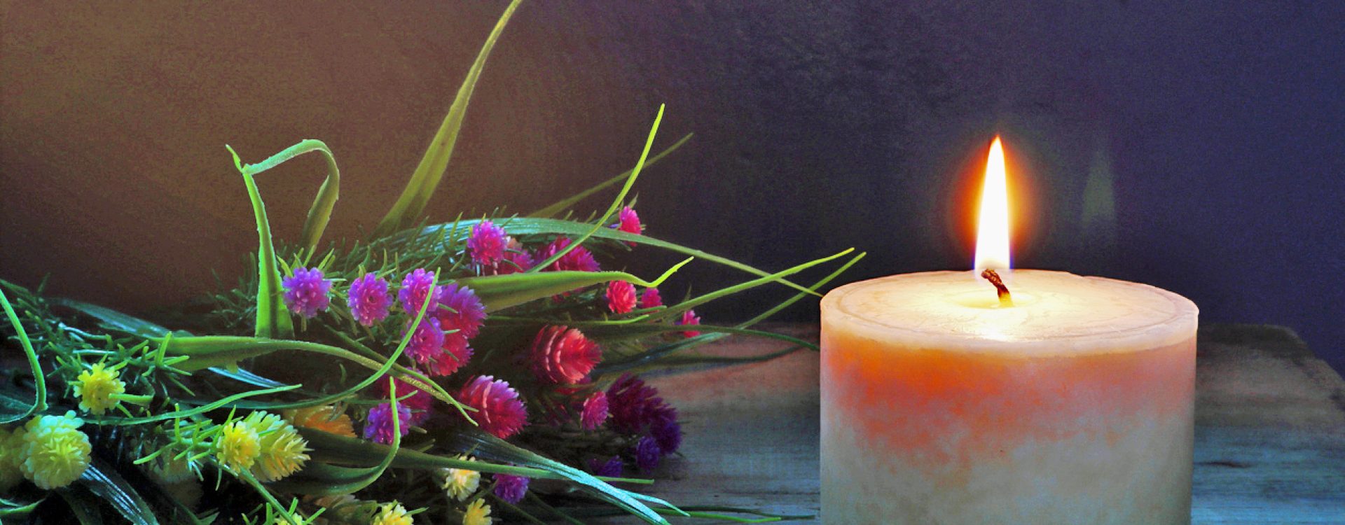 Single lit candle with dried flowers