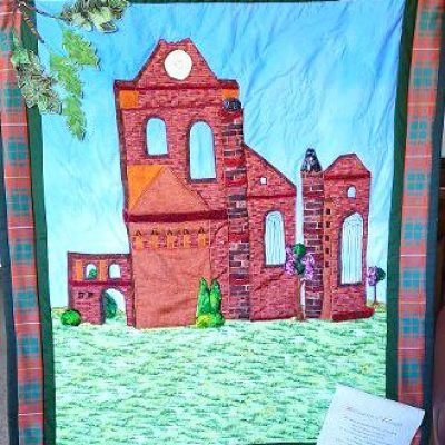 Beautiful quilt of Arbroath Abbey with 3-D aspects framed with the Bruce tartan