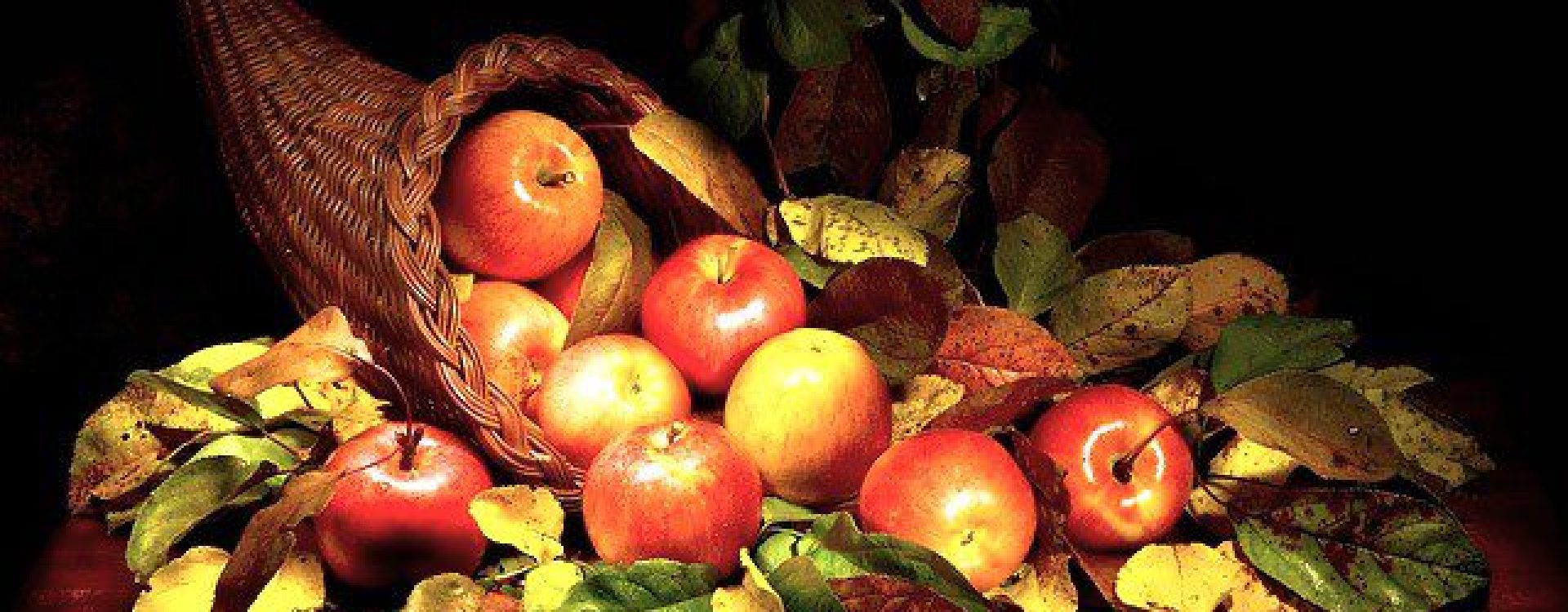 Cornucopia filled with red shiny apples and bright green leaves